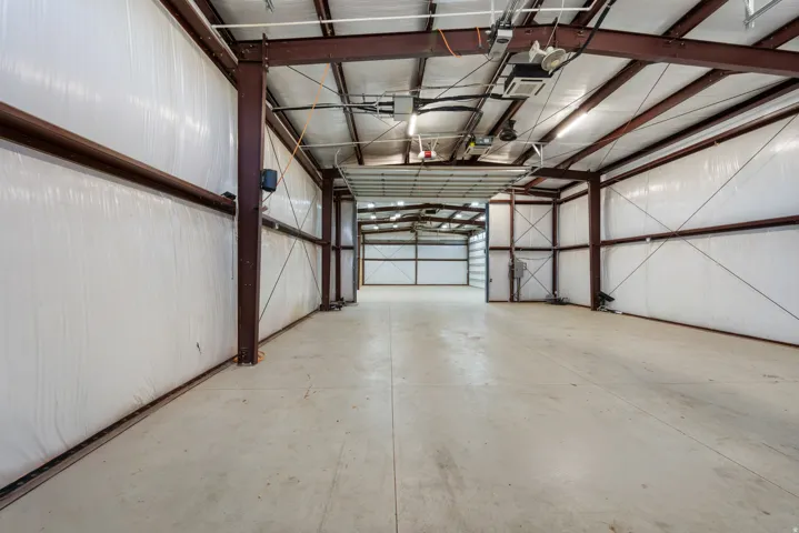 Expansive interior space featuring exposed steel beams, concrete flooring, and multiple garage doors