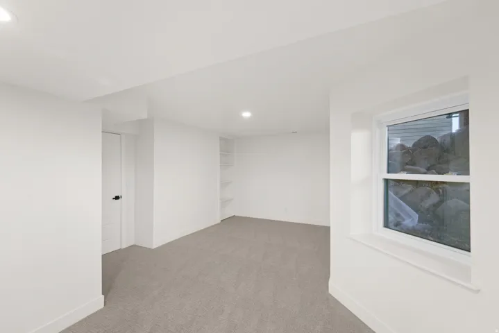 Recessed lighting, light gray carpet, and a built-in shelving unit