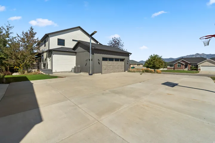 Two-story property with light-toned horizontal siding, dark vertical siding, and a multi-car concrete driveway