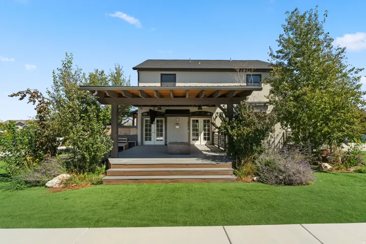 Expansive rear patio featuring a wood pergola, tiered composite decking, and integrated fire pit