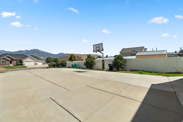 Expansive concrete pad, white privacy fencing, and a permanent basketball hoop