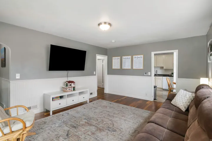 Hardwood-style flooring in main living area, white wainscoting, and recessed wall archway