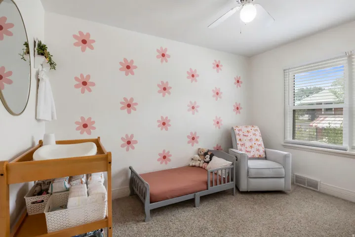 Textured carpet flooring, white walls, ceiling fan with integrated lighting, and a single window with blinds