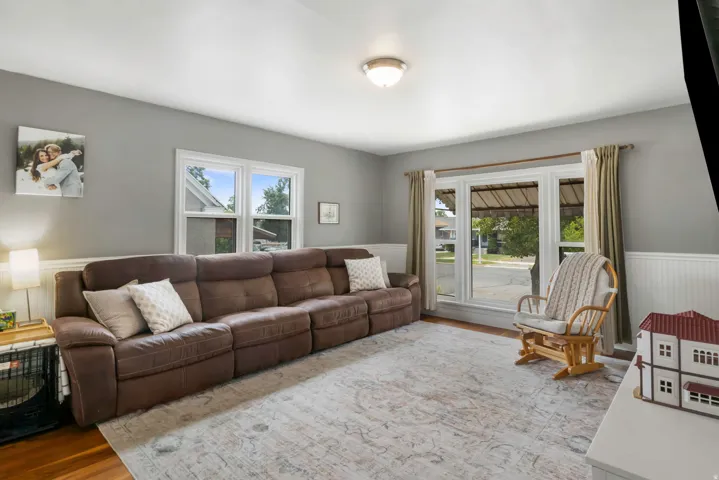 Living area with wood-finish flooring, two window units, and white wainscoting
