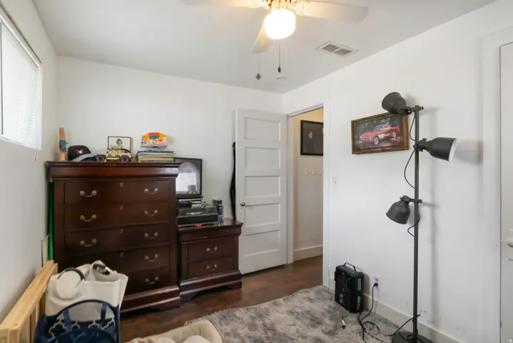 White walls, wood-finish flooring, ceiling fan with integrated lighting, and a window with blinds