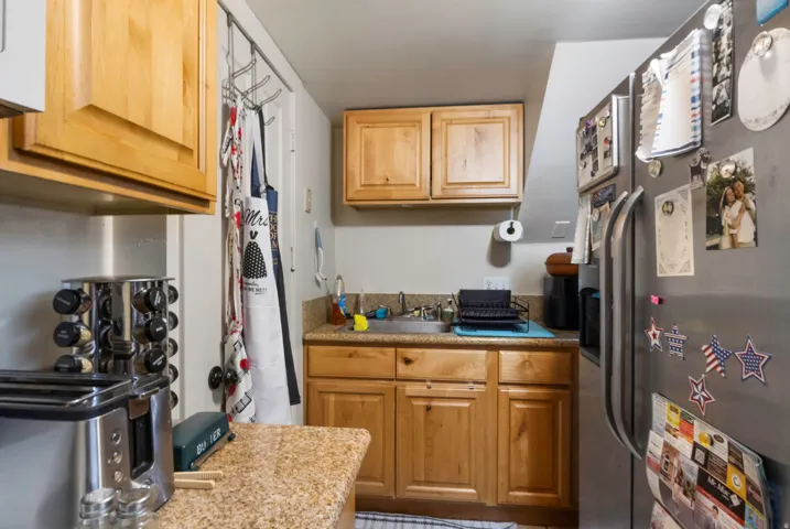 Wood-finish cabinetry, stainless steel sink, granite-patterned countertop