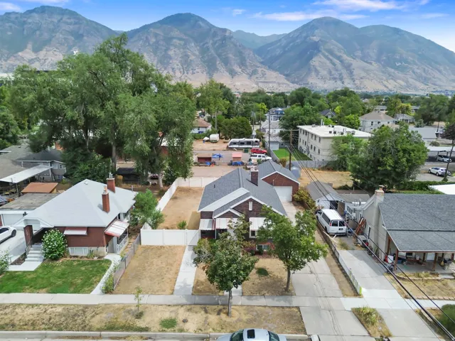 Mountain backdrop, residential setting, established tree cover, adjacent paved road, detached garage