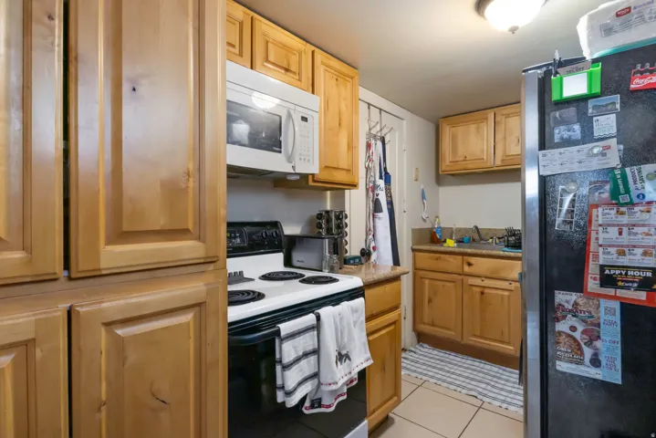 Light wood-finish cabinetry, white over-the-range microwave, built-in electric range, and solid surface countertops