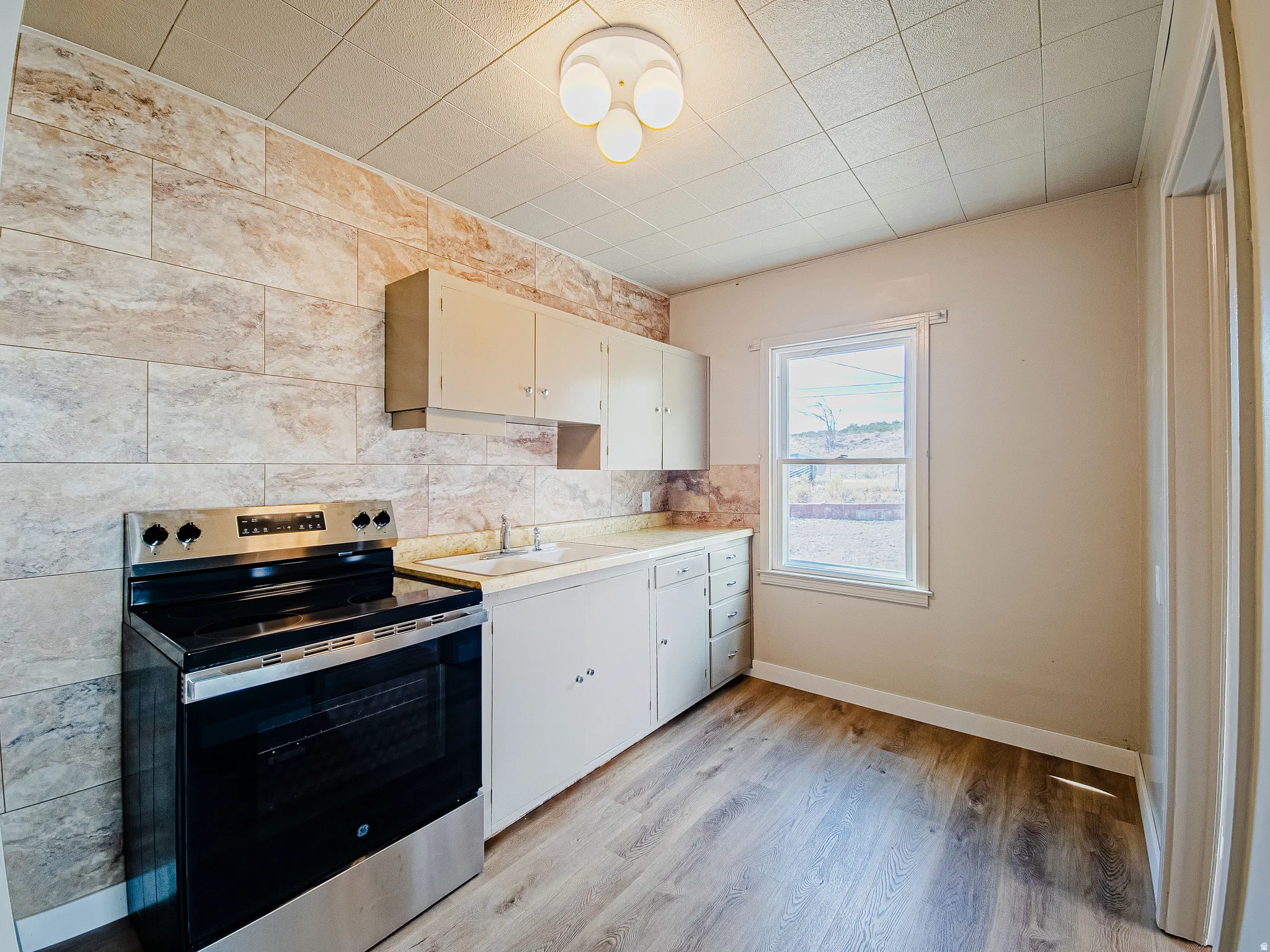 Kitchen featuring wood-finish flooring, a stainless steel range, and light-toned cabinetry