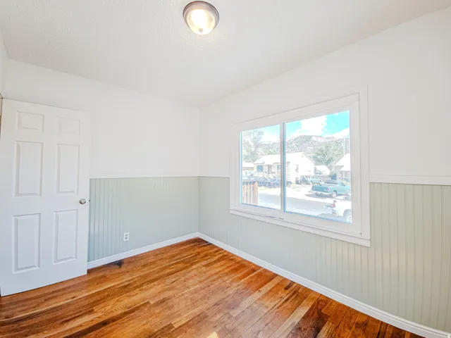 Hardwood flooring, beadboard wall paneling, white interior door, recessed wall outlet, flush-mount ceiling light