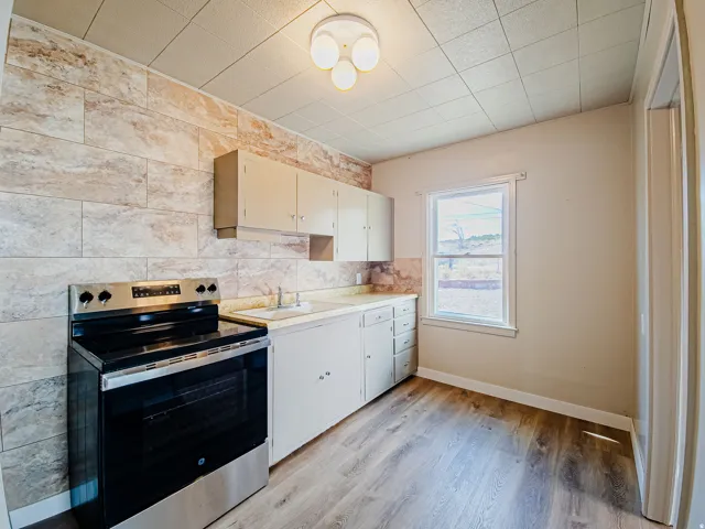 Kitchen featuring wood-finish flooring, a stainless steel range, and light-toned cabinetry
