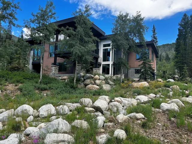 Modern exterior architecture with expansive windows, wood-finish siding, and stone accents
