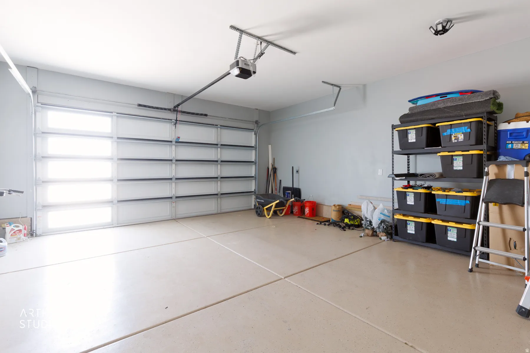 Two-car garage featuring a modern garage door with frosted glass panels, an automatic garage door opener, and concrete flooring
