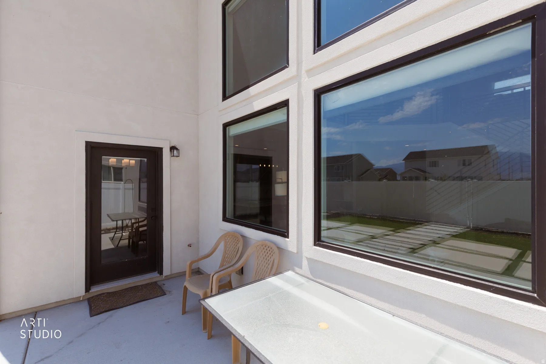 Patio with a full-light exterior door, exterior wall-mounted light fixture, and large multi-pane windows