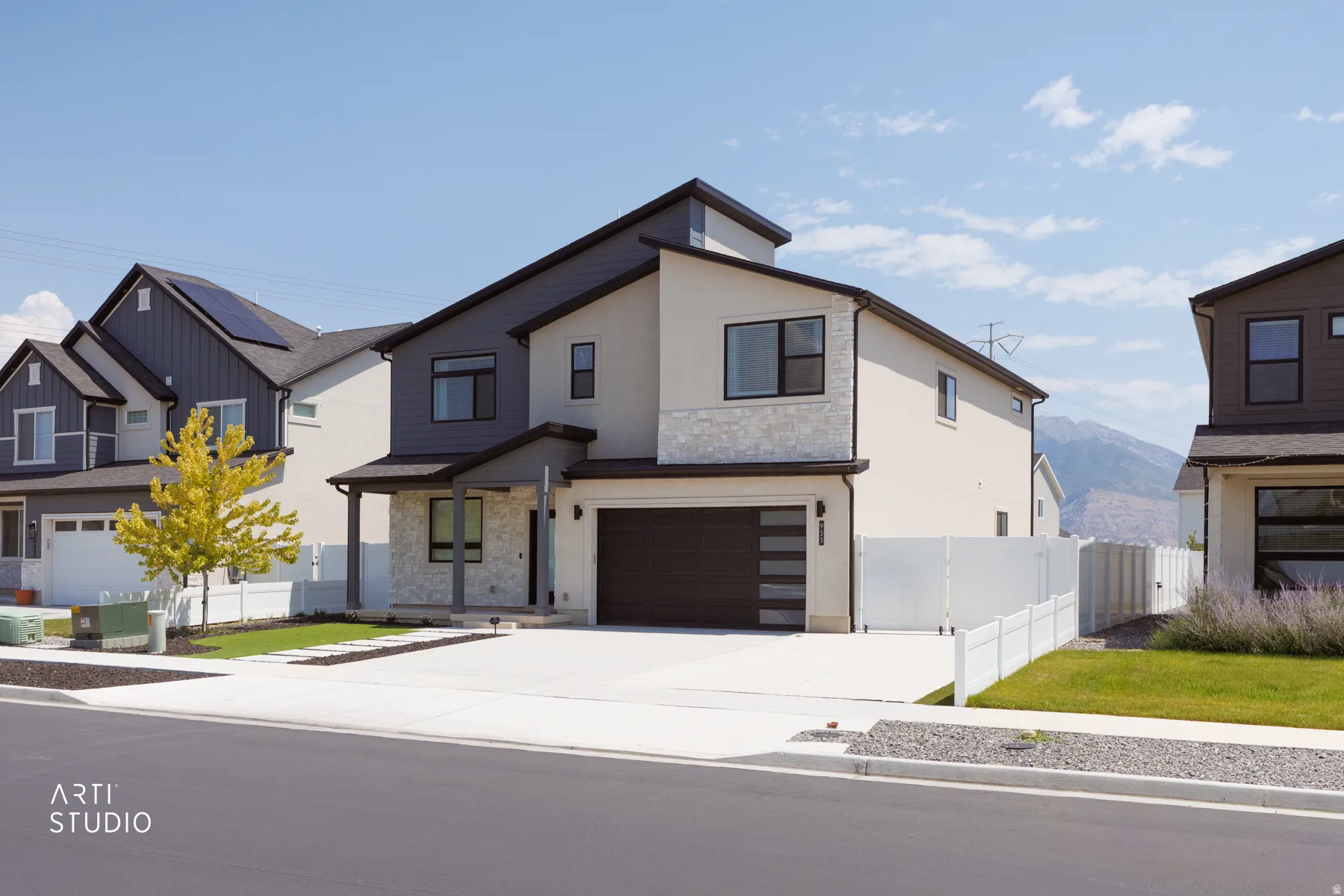 Contemporary architectural style with a stucco and stone facade, dark-frame windows, and a segmented garage door