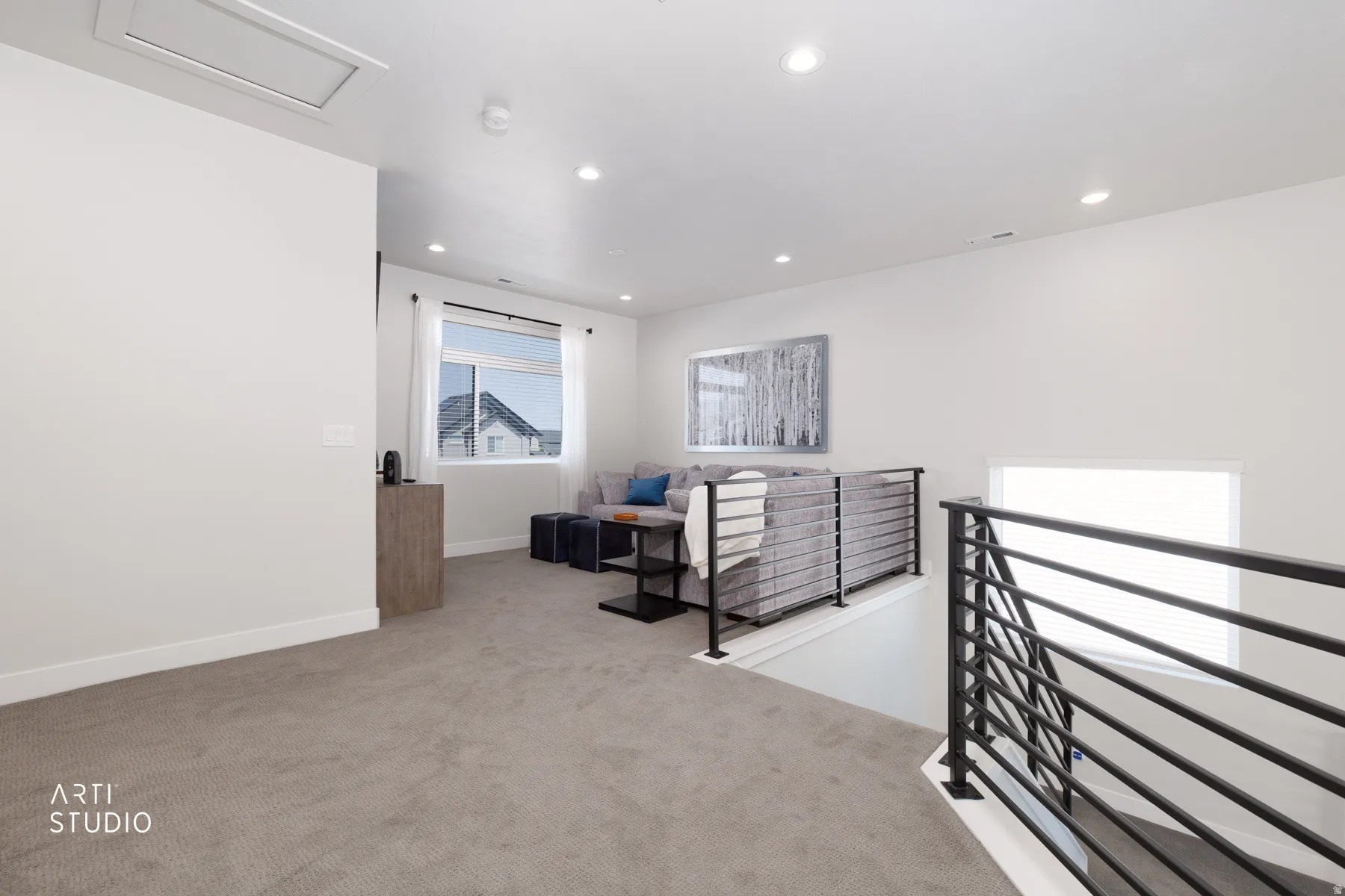 Open loft area featuring a black metal railing, recessed lighting, and a large window