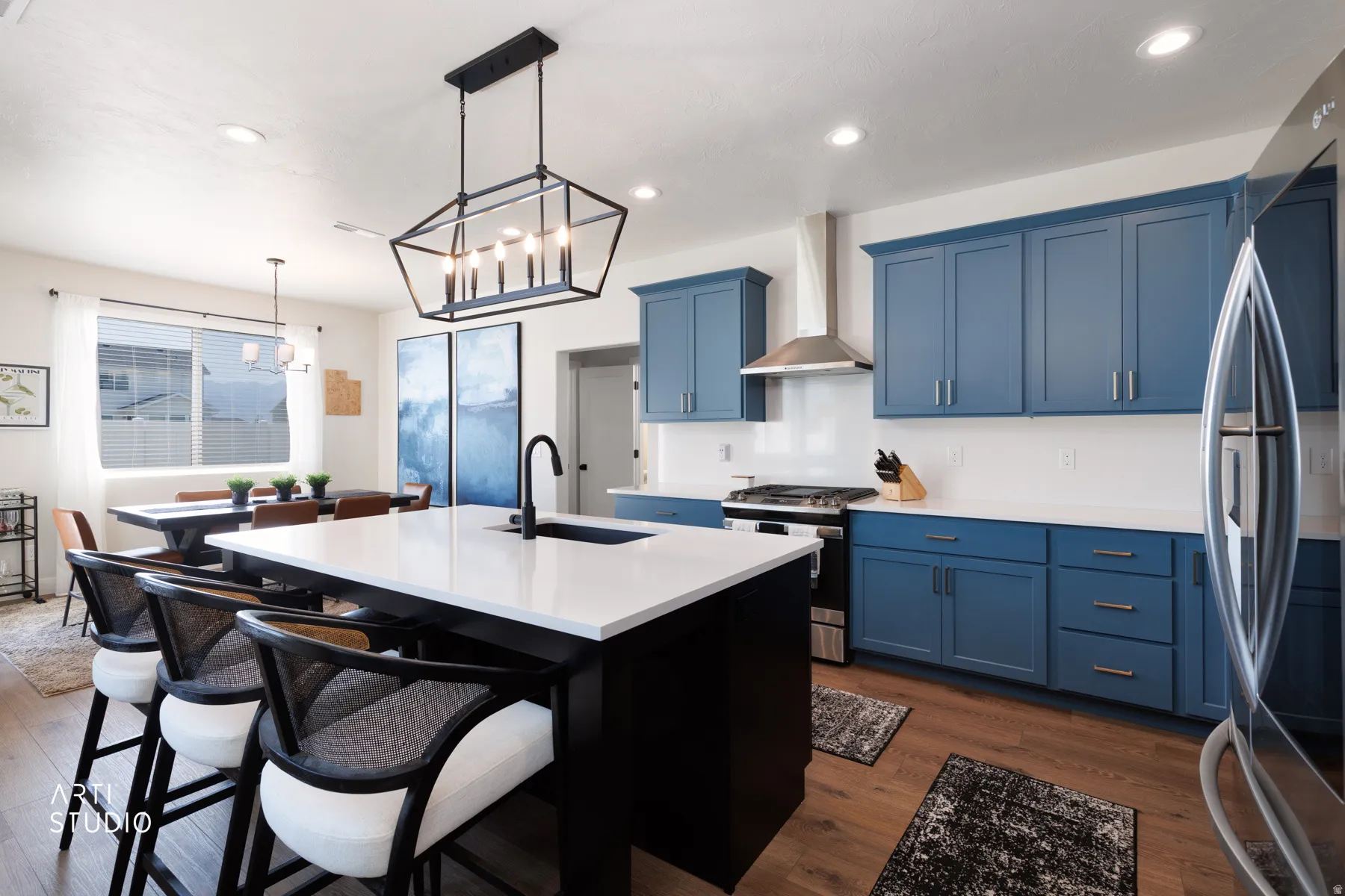 Kitchen featuring blue cabinetry, a central island with a white countertop, a stainless steel range hood, wood-finish flooring, and recessed lighting