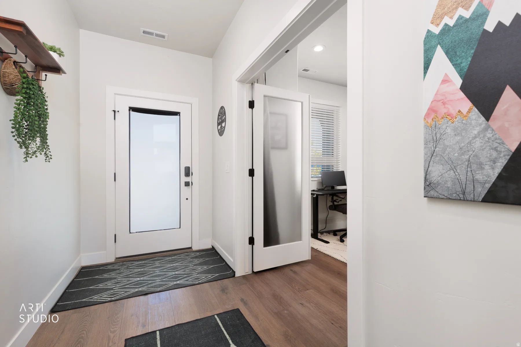 Wood-finish flooring, white paneled doors, and a translucent glass entry door