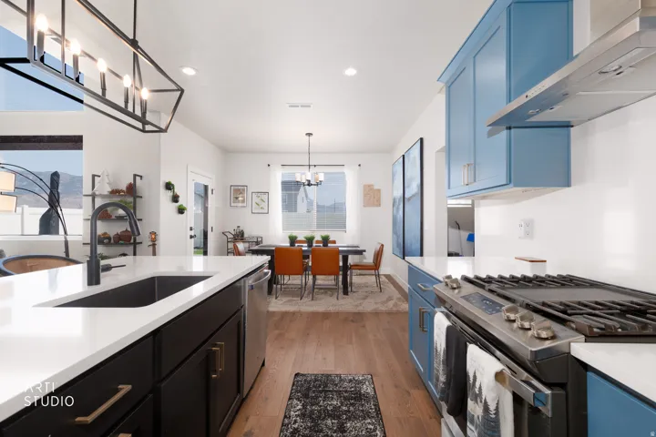 Kitchen featuring a large island with an undermount sink, stainless steel appliances, blue and dark cabinetry, and wood-finish flooring