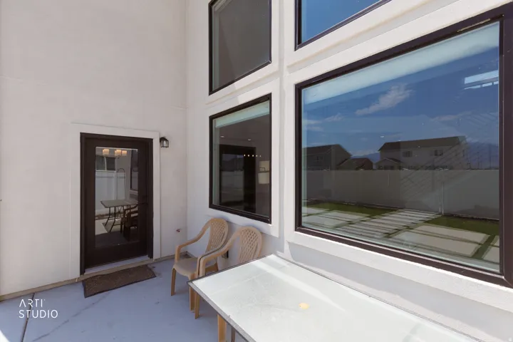 Patio with a full-light exterior door, exterior wall-mounted light fixture, and large multi-pane windows
