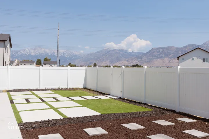 Expansive backyard featuring a white privacy fence, concrete stepping stones, and a manicured lawn