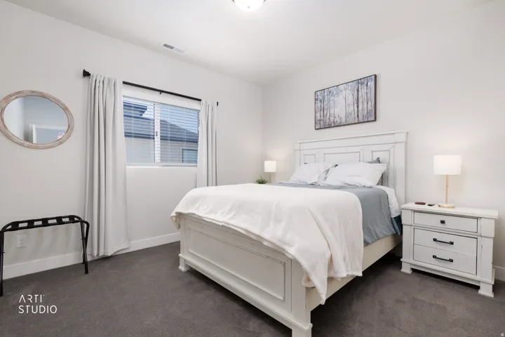 Spacious room with plush gray carpeting, a large window with blinds, and white painted walls