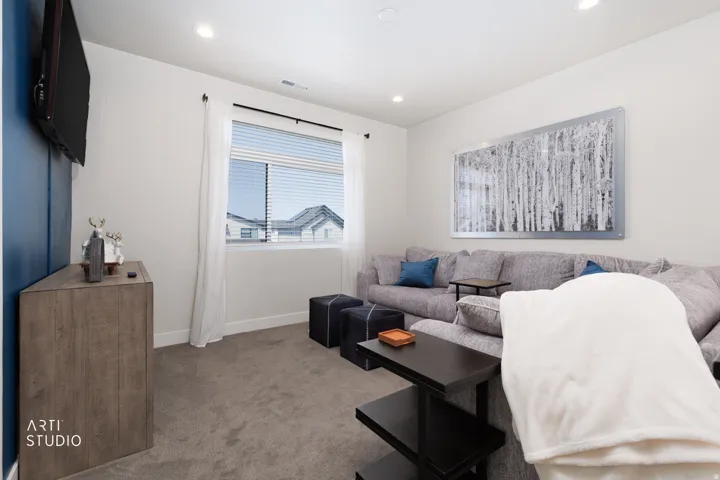 Carpeted room featuring a window with blinds, recessed lighting, and a wall-mounted display