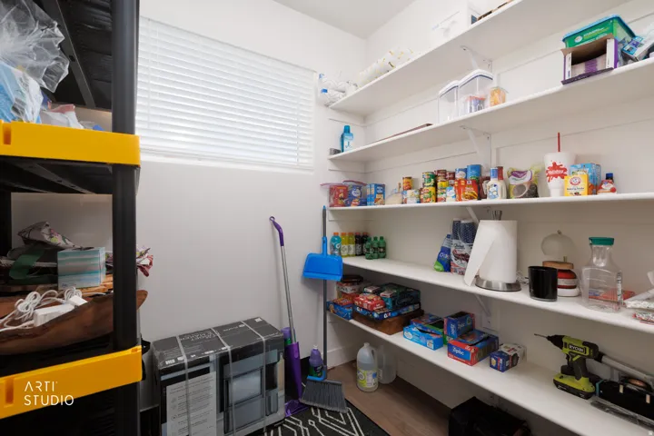 Window with horizontal blinds, built-in wall shelving, and wood-finish flooring