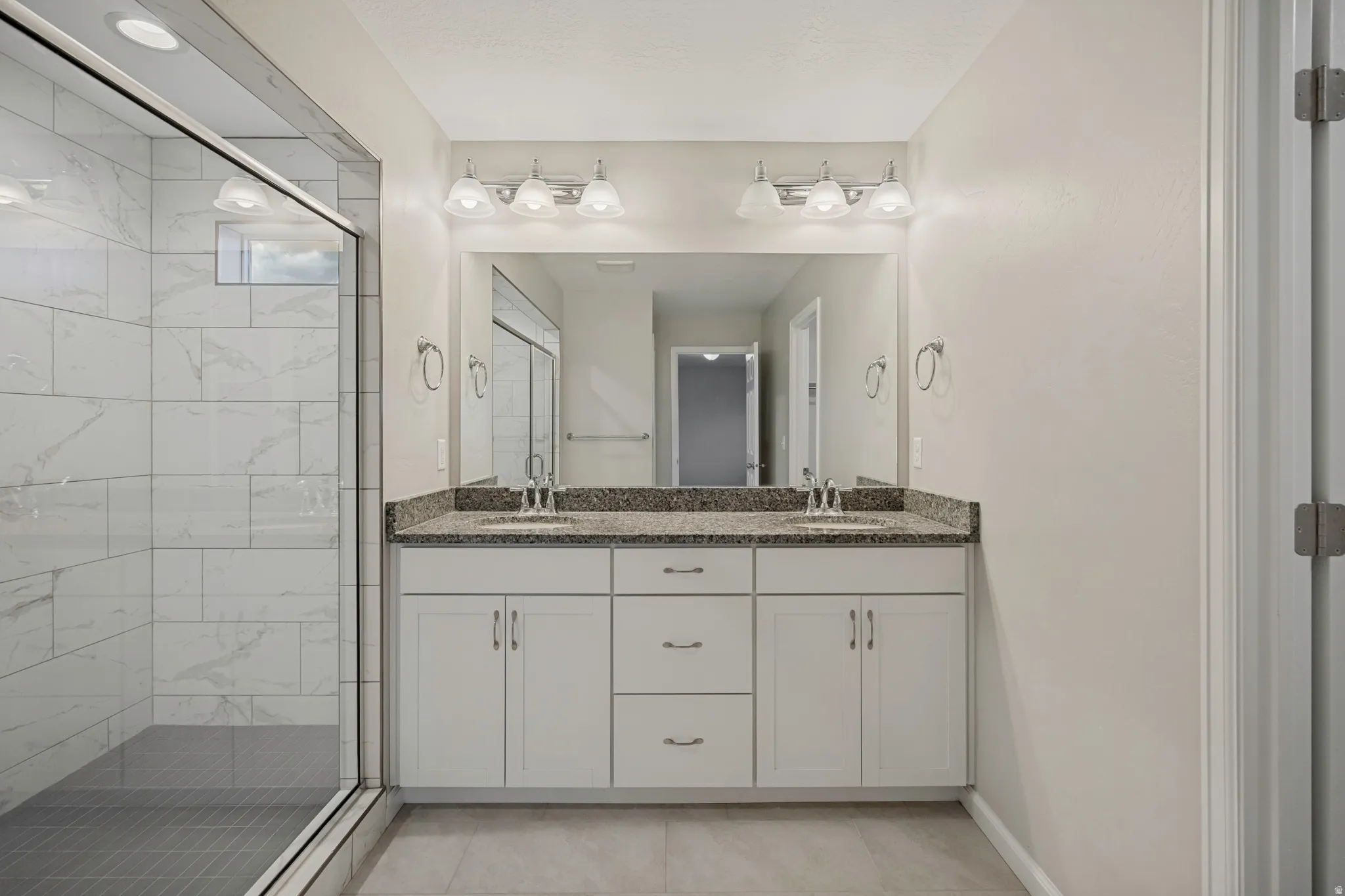 Double vanity with granite countertop, white cabinetry, and undermount sinks