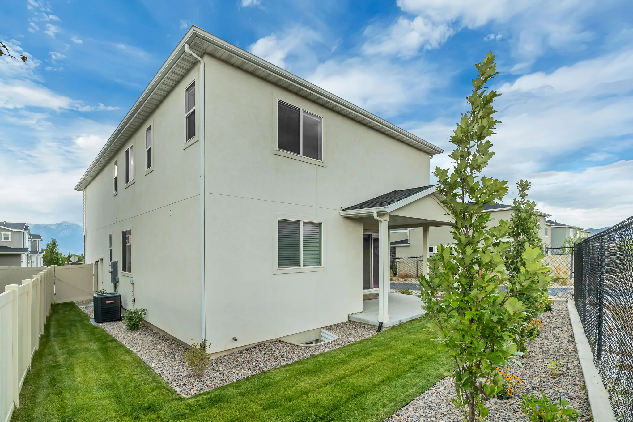 Two-story exterior with a covered patio, manicured lawn, and gravel landscaping