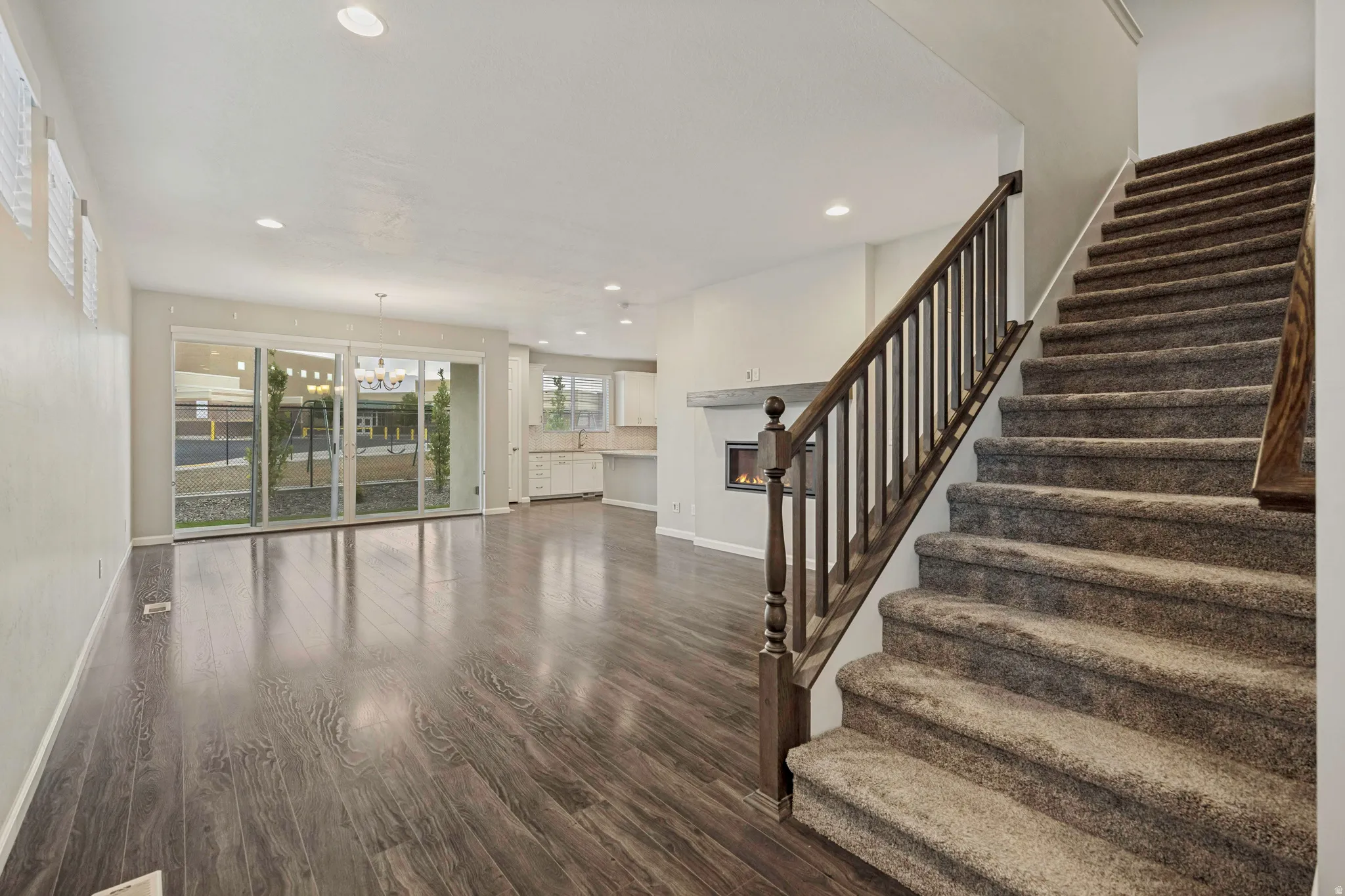 Spacious open-concept living area featuring wood-finish flooring, a contemporary fireplace, and large sliding glass doors