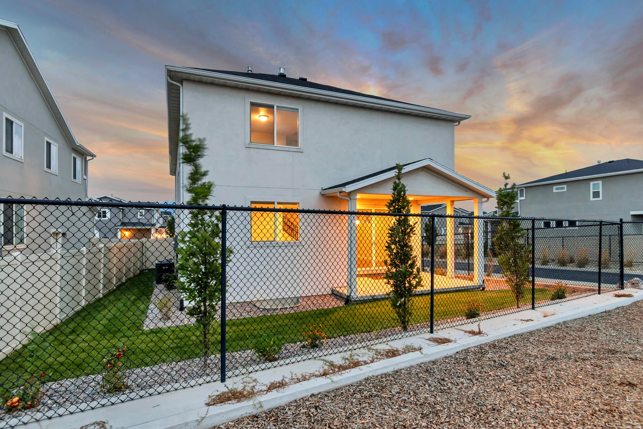 Rear elevation featuring a covered patio, fenced yard, and manicured landscaping