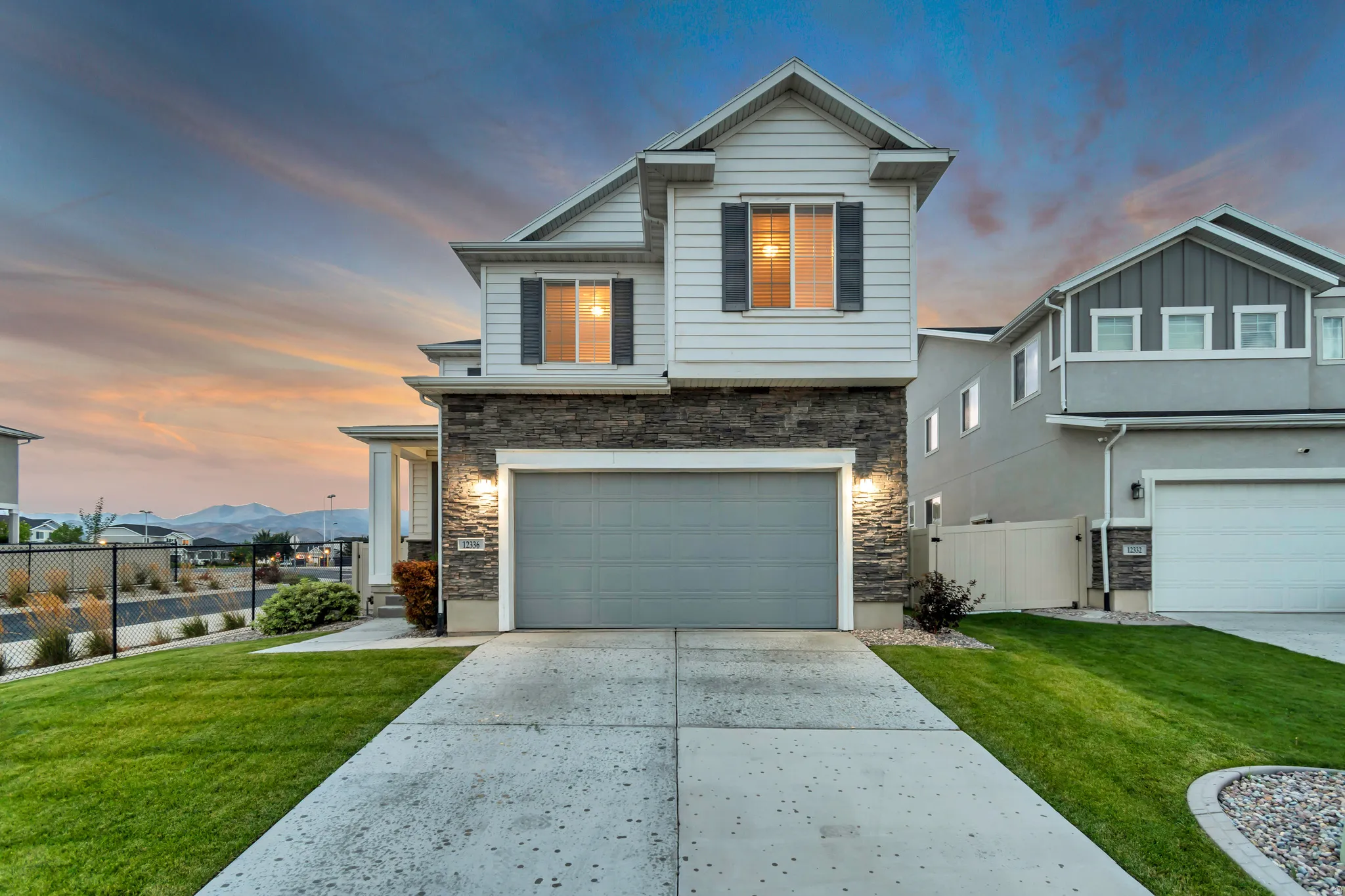 Modern exterior featuring stone and siding, an attached garage, and a concrete driveway