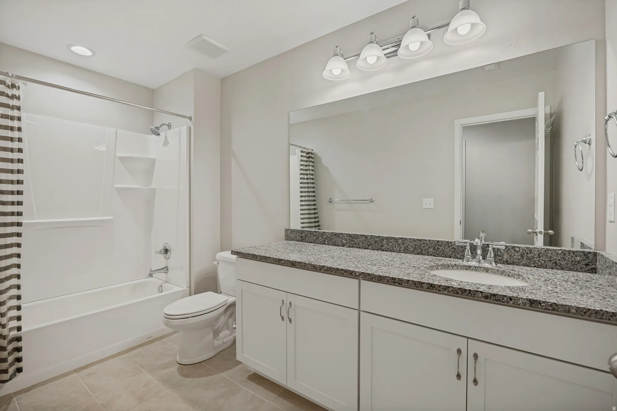 Double vanity with granite-style countertop, white cabinetry, and undermount sink