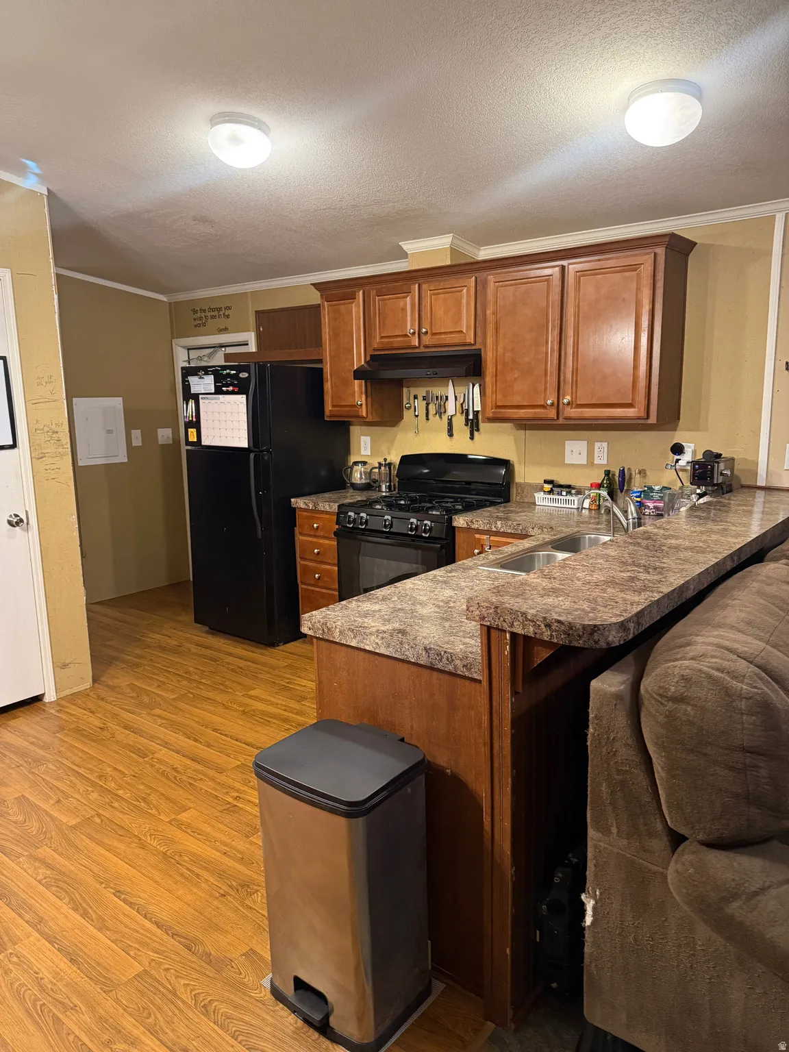 Kitchen featuring wood-finish flooring, brown cabinetry, and a countertop with an integrated double basin sink