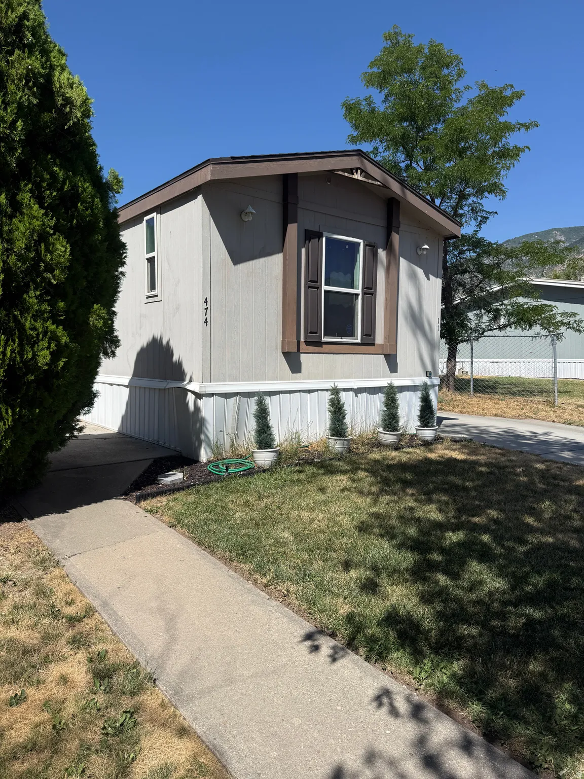 Property exterior with light-colored siding, brown trim, and a paved walkway