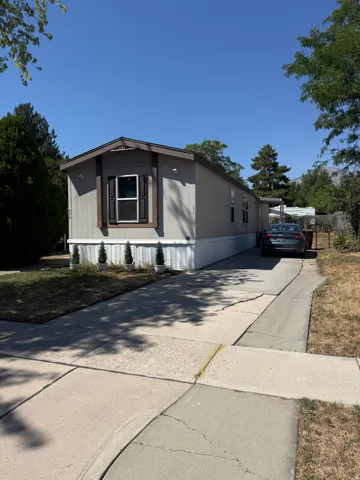 Single-story residence featuring light-colored siding, dark window shutters, and a pitched roof