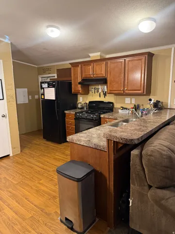 Kitchen featuring wood-finish flooring, brown cabinetry, and a countertop with an integrated double basin sink