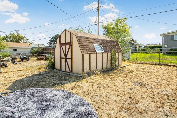 Detached storage shed with a gambrel roof and a single window
