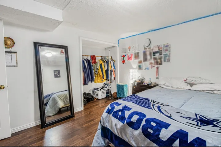 Wood-finish flooring with white walls and a built-in closet space
