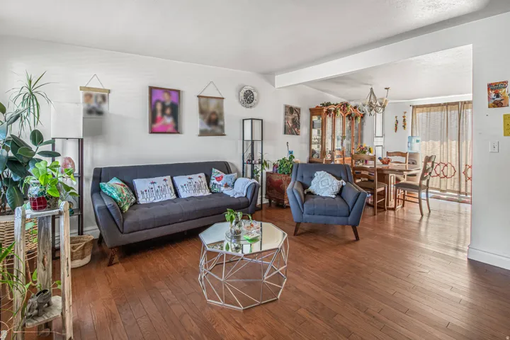 Hardwood-finish flooring throughout, bright white walls, and an open entryway to an additional living space