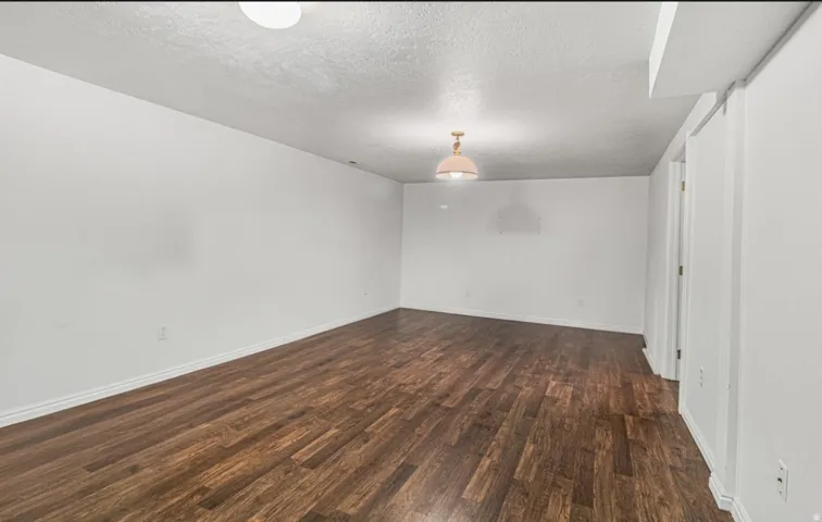Spacious room featuring wood-finish flooring, white walls, and recessed lighting
