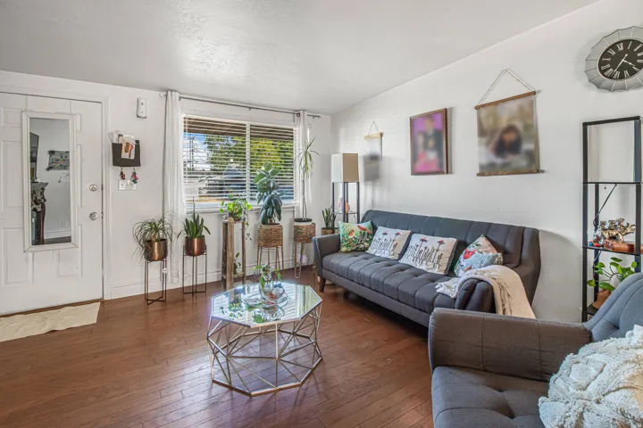 Wood-finish flooring throughout, white paneled door, and a large window with blinds