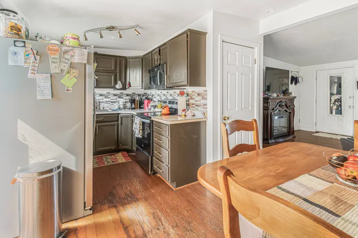 Kitchen featuring wood-finish flooring, dark cabinetry, and a patterned tile backsplash