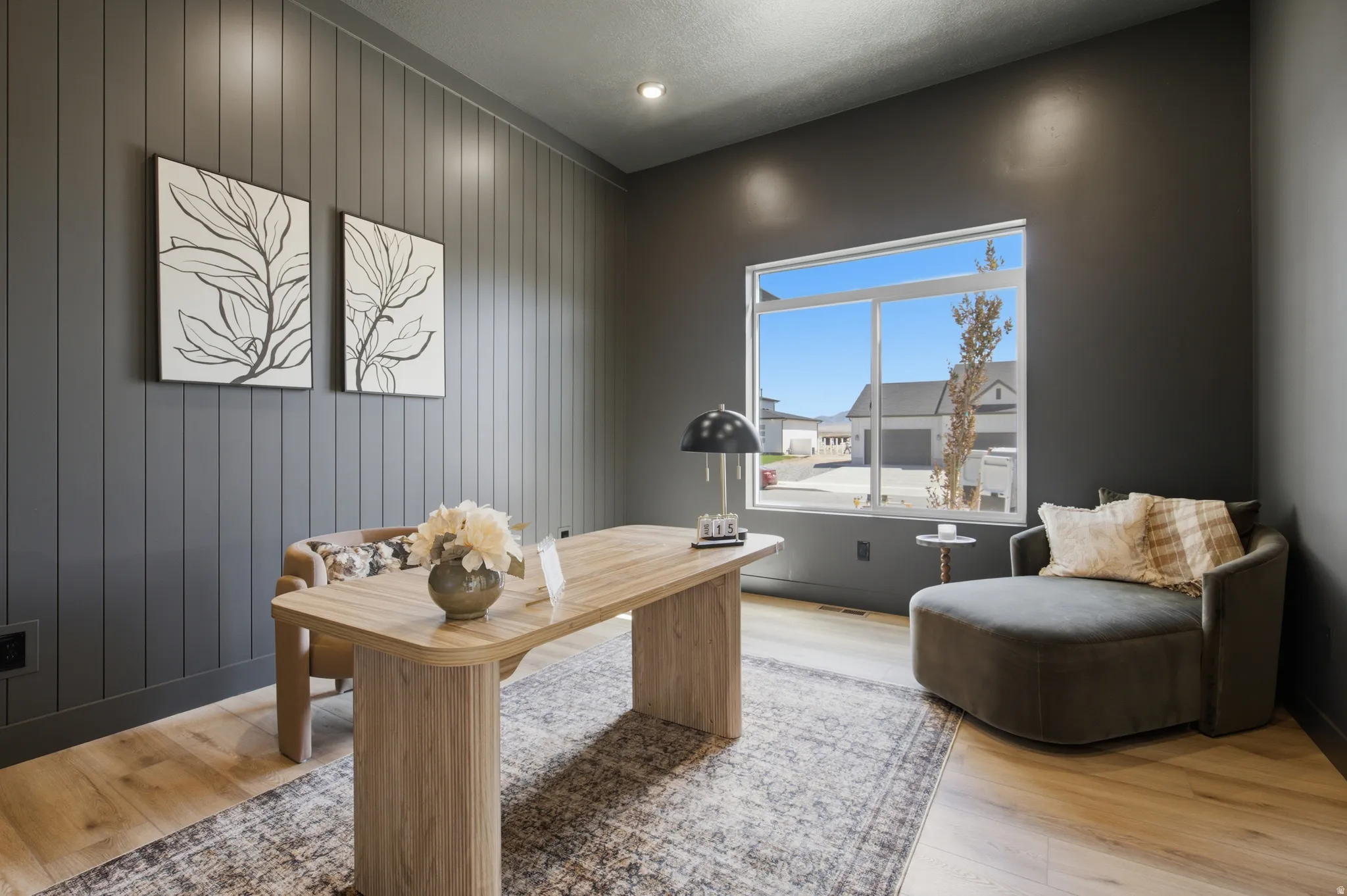 Accent wall with vertical paneling, light wood-finish flooring, recessed ceiling lighting, large window, and dark painted walls