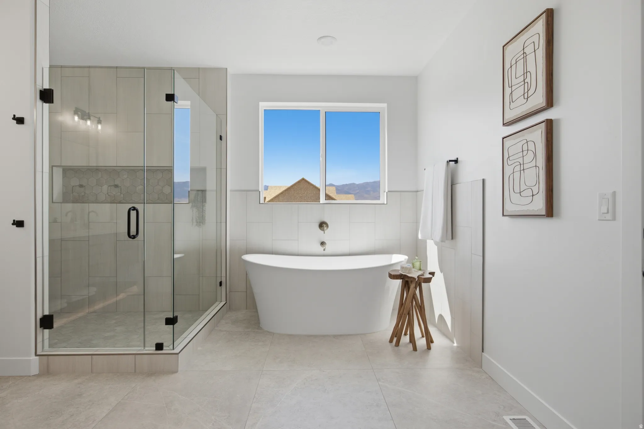 Glass-enclosed shower with tile surround and built-in niche, featuring a wall-mounted light fixture and matte black hardware