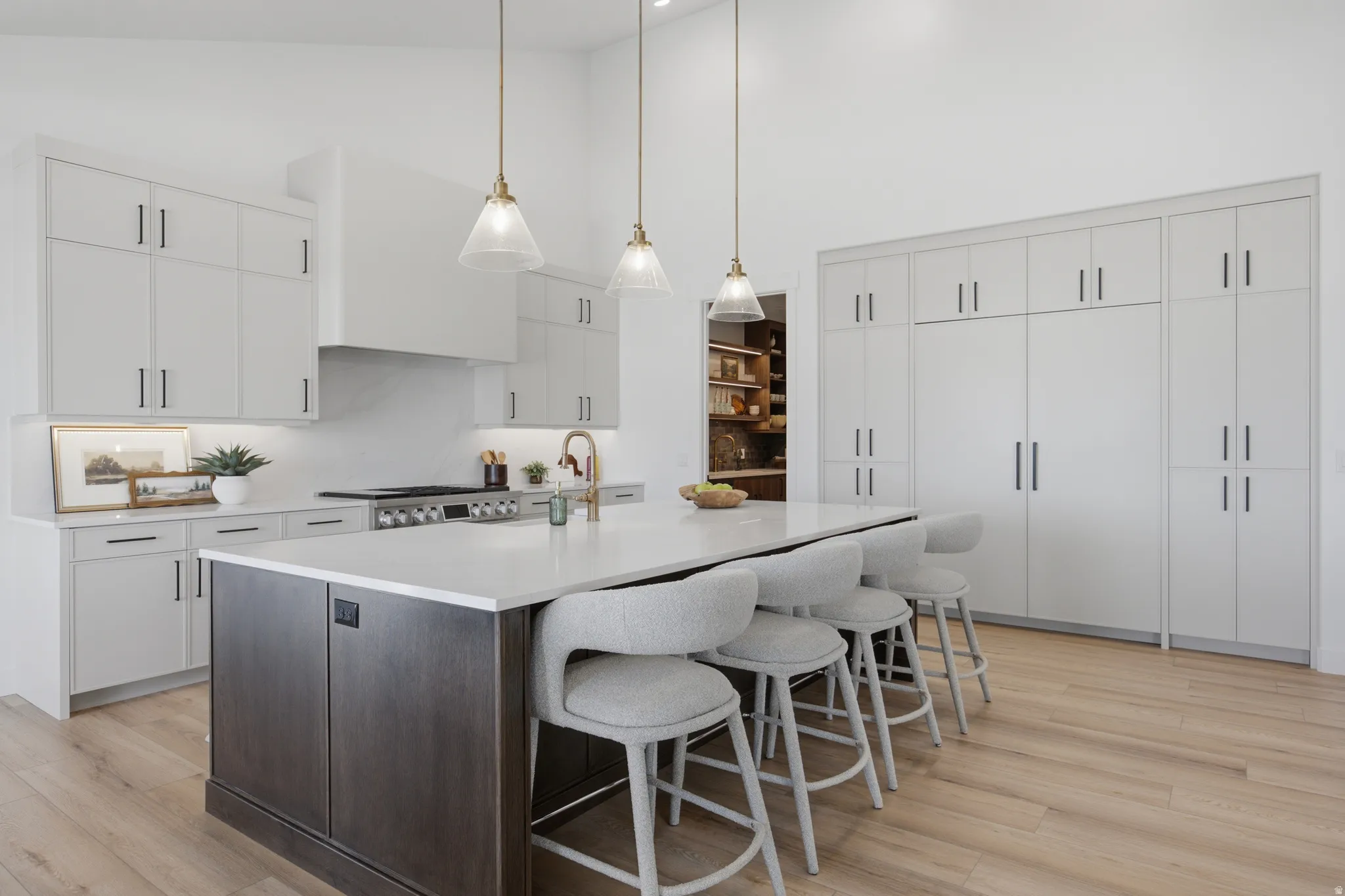 Kitchen featuring light wood-finish flooring, a substantial center island with a light-toned countertop, extensive built-in cabinetry, and integrated ceiling lighting