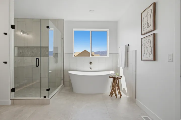 Glass-enclosed shower with tile surround and built-in niche, featuring a wall-mounted light fixture and matte black hardware
