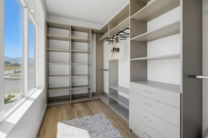 Built-in custom shelving, integrated drawer storage, wood-finish flooring, and large window
