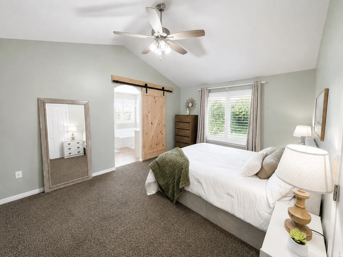 Vaulted ceiling with a ceiling fan, carpet flooring, window with white blinds, and a wood-finish barn door